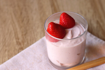 Bowl of strawberry yogurt with two fresh strawberries on the top. Selective focus.