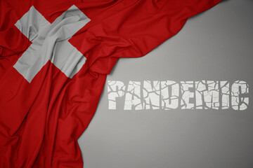 waving colorful national flag of switzerland on a gray background with broken text pandemic. concept.