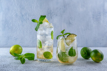 Cocktail Mojito. Cocktail with rum, mint, lime and ice in a glass on a grey background. Homemade beverage.