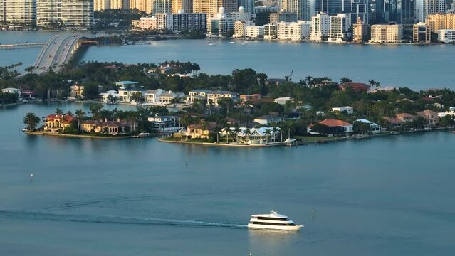 Expensive waterfront houses on Bird Key in Sarasota city in Florida, USA. Large cruise yacht siling on bay waters and high-rise office buildings in downtown district on horizon. Recreational pursuit