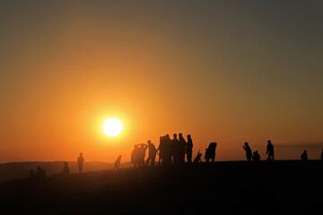 Fototapeta na wymiar silhouette of people at sunset in desert