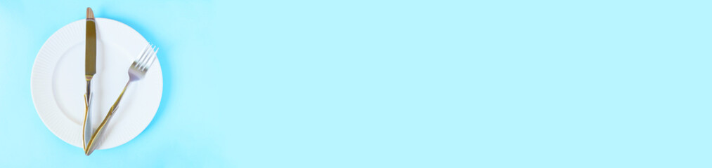 Intermittent fasting banner. Fork and knife on the plate flat lay