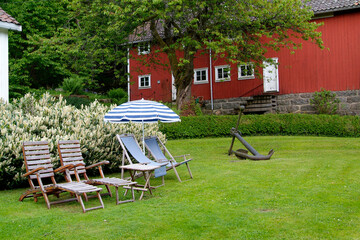 Four chairs, a parasol and an anchor in a green garden