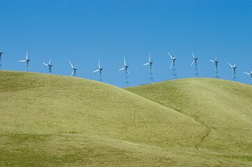 Fototapeta premium A line of windmills on rolling hills in California.