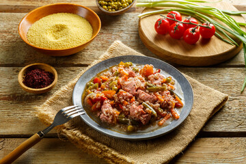 Israeli couscous in spices with sumac and chicken pieces on a linen napkin next to couscous, sumac and vegetables.