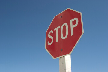 A authoritatively low angle view of stop sign against a very blue sky.