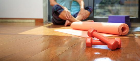 Yoga mat and dumbbells on wooden floor