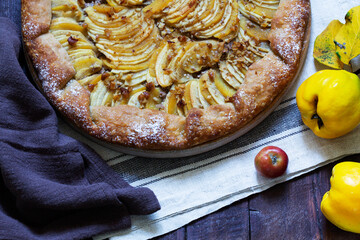 Open pie stuffed with apples, quince and nuts on a wooden background. Rustic style.