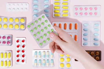 Hand holding pills in blister packs on a pink background. Health care concept. Top view. - obrazy, fototapety, plakaty