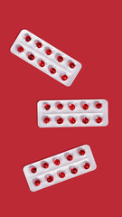 Round red translucent pills in blister packs on a red background