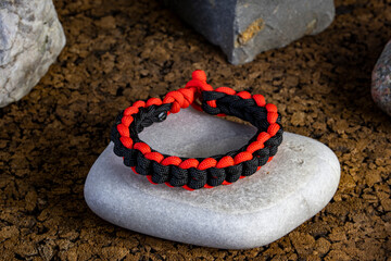 Braided paracord bracelet on the background of stones. Handmade, creative design.