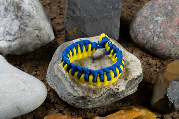 Braided paracord bracelet on the background of stones. Handmade, creative design.