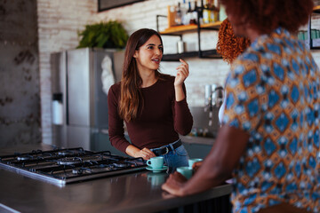 Three diverse friends talking in kitchen.
