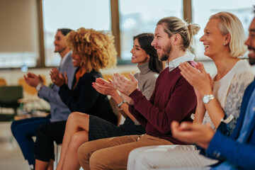 Excited audience clapping in meeting.