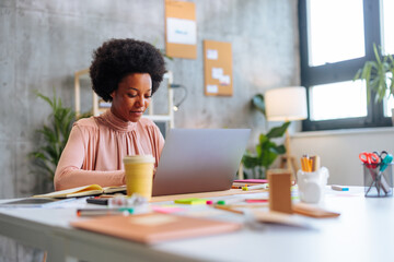 African-American business woman using company laptop while sitting in corporate office.