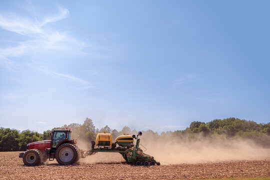 A vibrant spring scene unfolds as a tractor diligently plants seeds in a vast field, exemplifying the essence of agriculture and growth in a rural landscape.