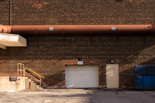 The back alley behind a commercial business with a roll-up garage door. 