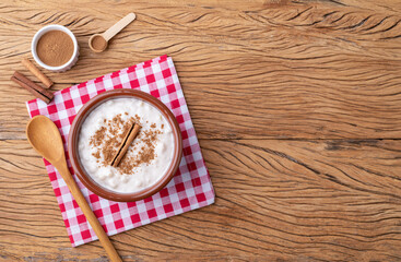 Canjica or munguza, typical brazilian white corn sweet cream with cinnamon over wooden table with copy space