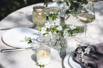 Rustic zero waste wedding decor with natural elements. Fresh spring blooming flowers, candles, linen napkins, wine glasses. Eco friendly decoration for the special holiday dinner. Romantic cozy place