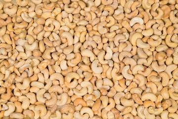 Delicious salted roasted cashews in texture pattern. Anacardium occidentale. Closeup of many salted cashew nuts of kidney shape in beige culinary background. Vegetarian food full of healthy nutrients.