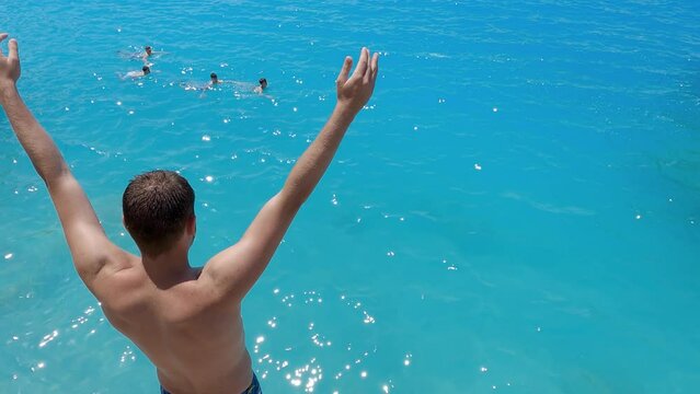 Athletic young man makes adrenaline head jump in clear turquoise water on Kathisma beach in Lefkada, Greece, slow motion