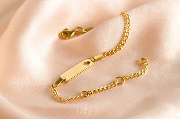 Golden bracelet with name plate with heart on a pink background. Romantic decorations. Сoncept for Valentine's Day