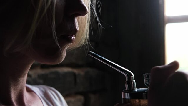 A woman smokes marijuana using a device. Cannabis use.