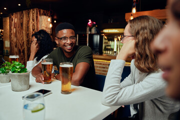 Happy young multiracial group of friends in casual clothing smiling and talking during celebration