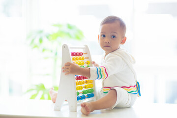 Baby boy playing with wooden abacus.