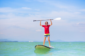 Child on stand up paddle. Water and beach sport