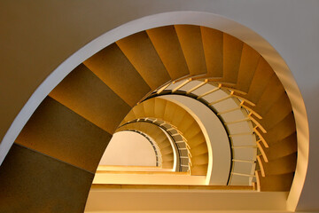 Fototapeta premium Spiral steps in a building with beautiful, warm lighting