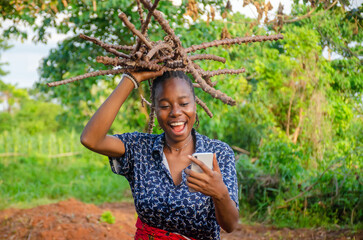 young african woman on a farm smiling using phone