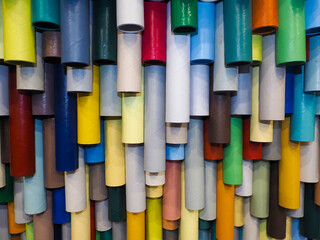 Colorful plastic pipes on the wall of a building .  Rolls of colored paper on a shelf in the store. Texture