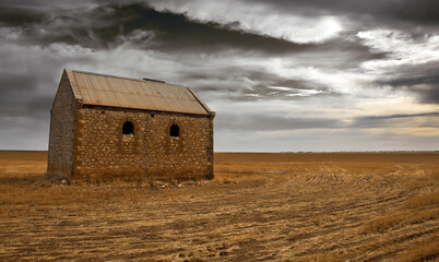 An old farm building surrounded by dark clouds