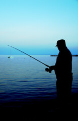 Silhouette of man fishing at dusk in peaceful conditions