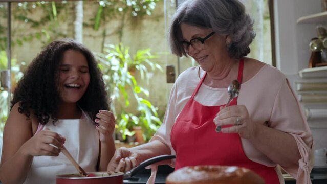 av&oacute; brasileiro brincando com sua neta na cozinha enquanto fazem brigadeiro no dia das m&atilde;es