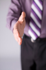 Man gaving his hand to shake; Focus on the fingers. Rest of the body unfocus.