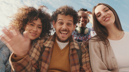 Happy smiling friends laughing outside at something in a laptop. Four students spending time together