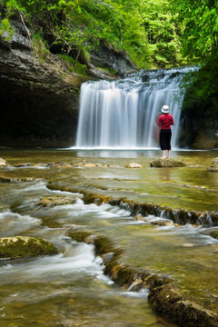 Barefoot woman standing on a stone at on of the beautiful Cascades du Herisson in France
