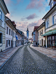 Obraz premium Vertical shot of the Cobblestone Sutna street old houses and shops with colorful cloud sky, Kamnik, Slovenia