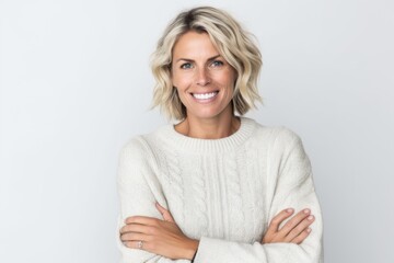 Portrait of smiling woman with arms crossed standing against white background.