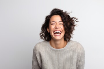 Portrait of a laughing young woman in sweater on white background.