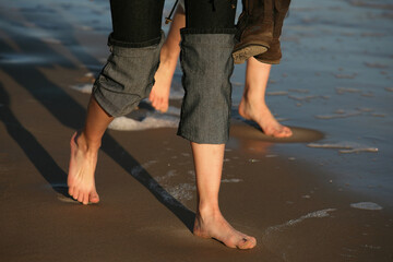 Two pairs female legs on wet sand