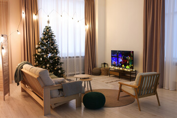 Wide TV set, furniture and Christmas tree in stylish room