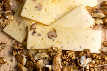 Sliced piece of milk cheese with walnuts