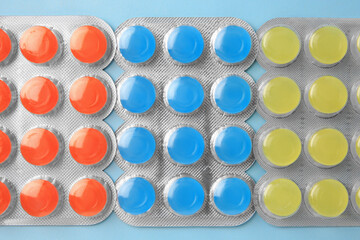 Blisters with cough drops on light blue background, flat lay