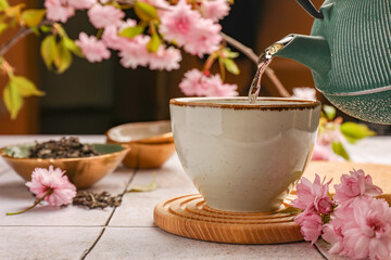 Traditional ceremony. Pouring brewed tea from teapot into cup on tiled table, closeup