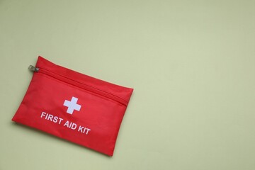 First aid kit on light green background, top view. Space for text