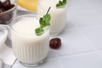Glass of delicious date smoothie with mint on white table, closeup. Space for text
