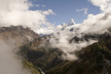 The trail from Namche Bazar to Phunki Tenga, Nepal. You can see Ama Dablam to the right and in the middle Nuptse, Lhotse, and Everest emerge from the clouds. - obrazy, fototapety, plakaty